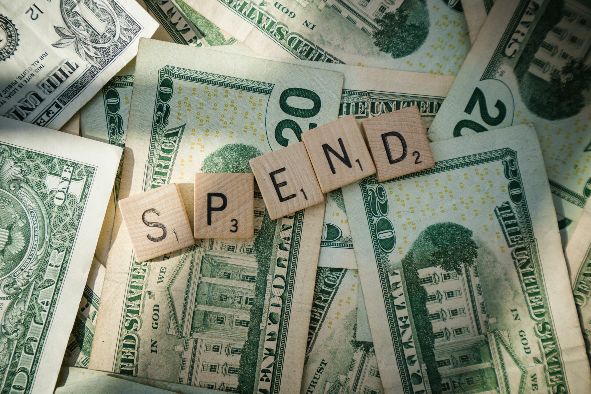 Scrabble letters spelling 'spend' on American bills