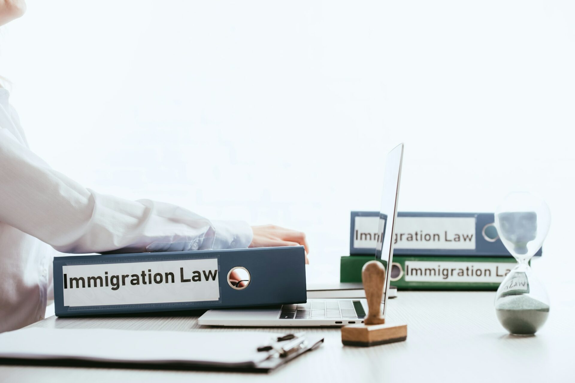 selective focus of woman taking folder with immigration law lettering near laptop isolated on white